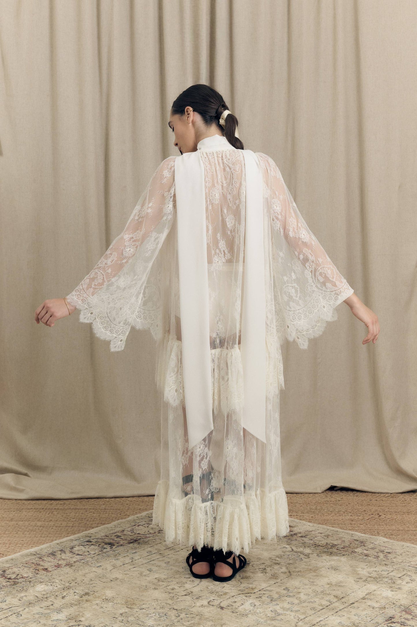 Model wearing Botteghe Oscure asymmetrical French Chantilly lace dress with silk scarf – back view