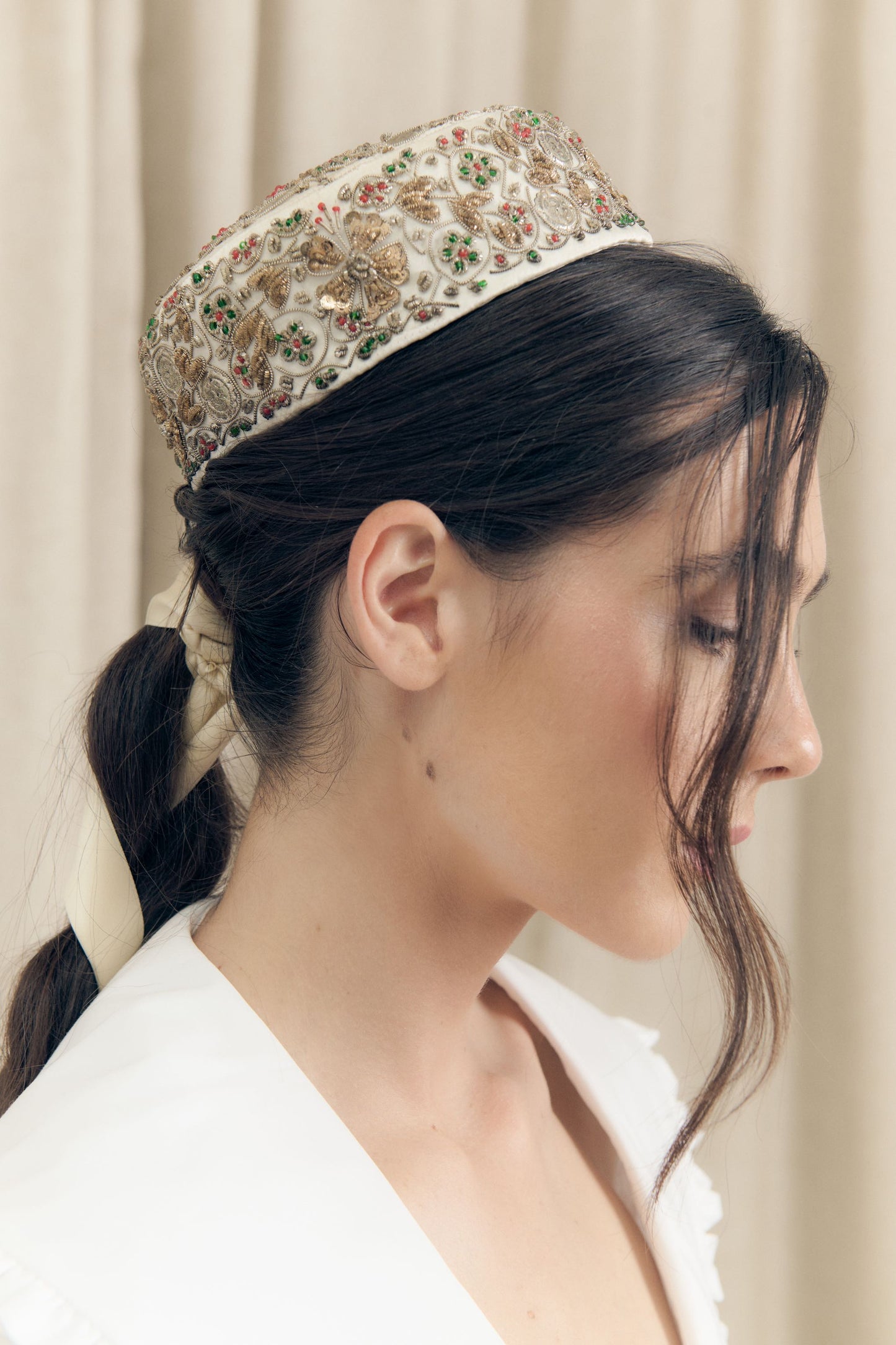 Profile view of embroidered smoking hat crafted from vintage silk with zardozi technique, floral and medallion motifs, worn on model.