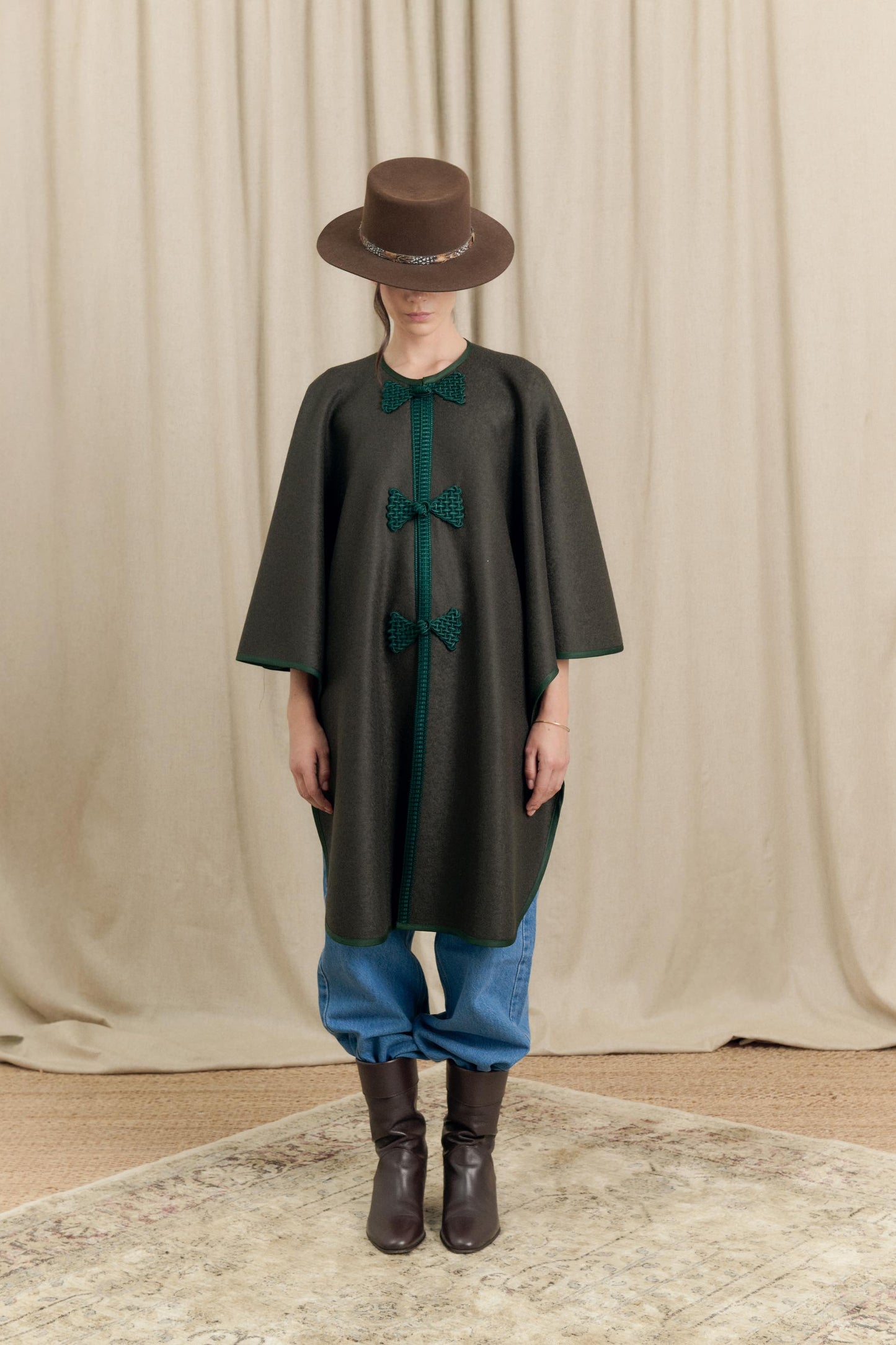Model wearing dark green Botteghe Oscure loden wool cape with handmade frog fastenings, front view