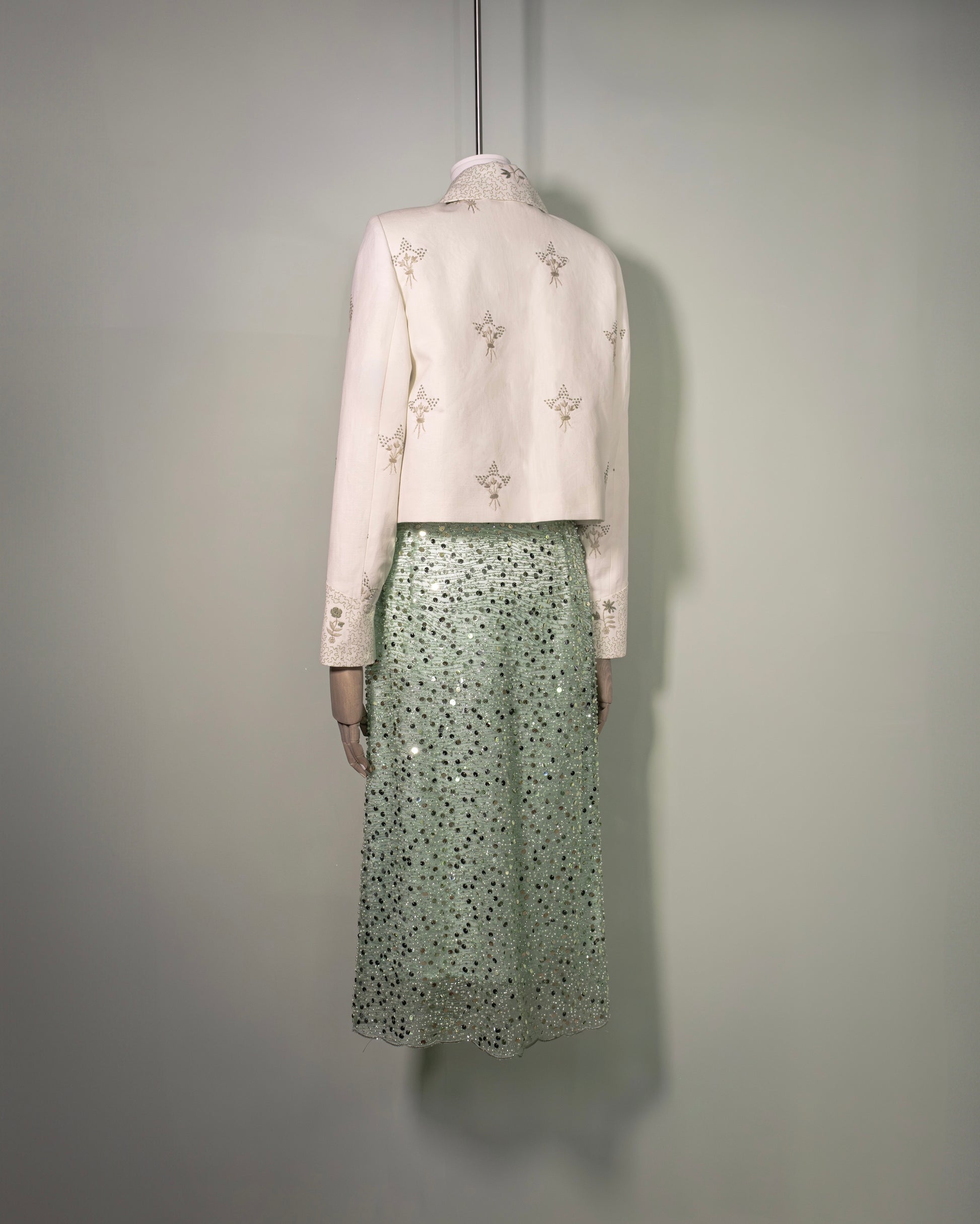 Botteghe Oscure Carré Jacket in archival English linen with hand-embroidered floral bouquets, styled with sequins embroidered skirt and silk flower brooch, front view.