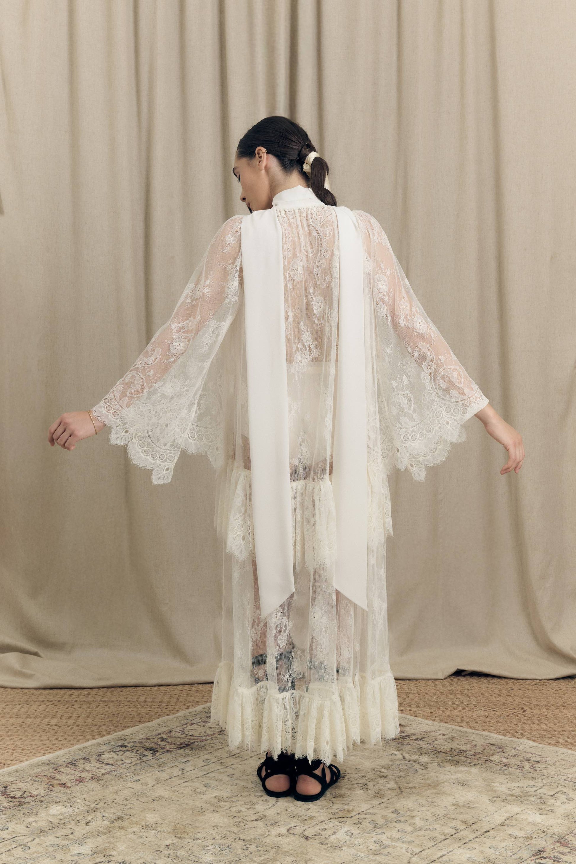 Model wearing Botteghe Oscure asymmetrical French Chantilly lace dress with silk scarf – back view