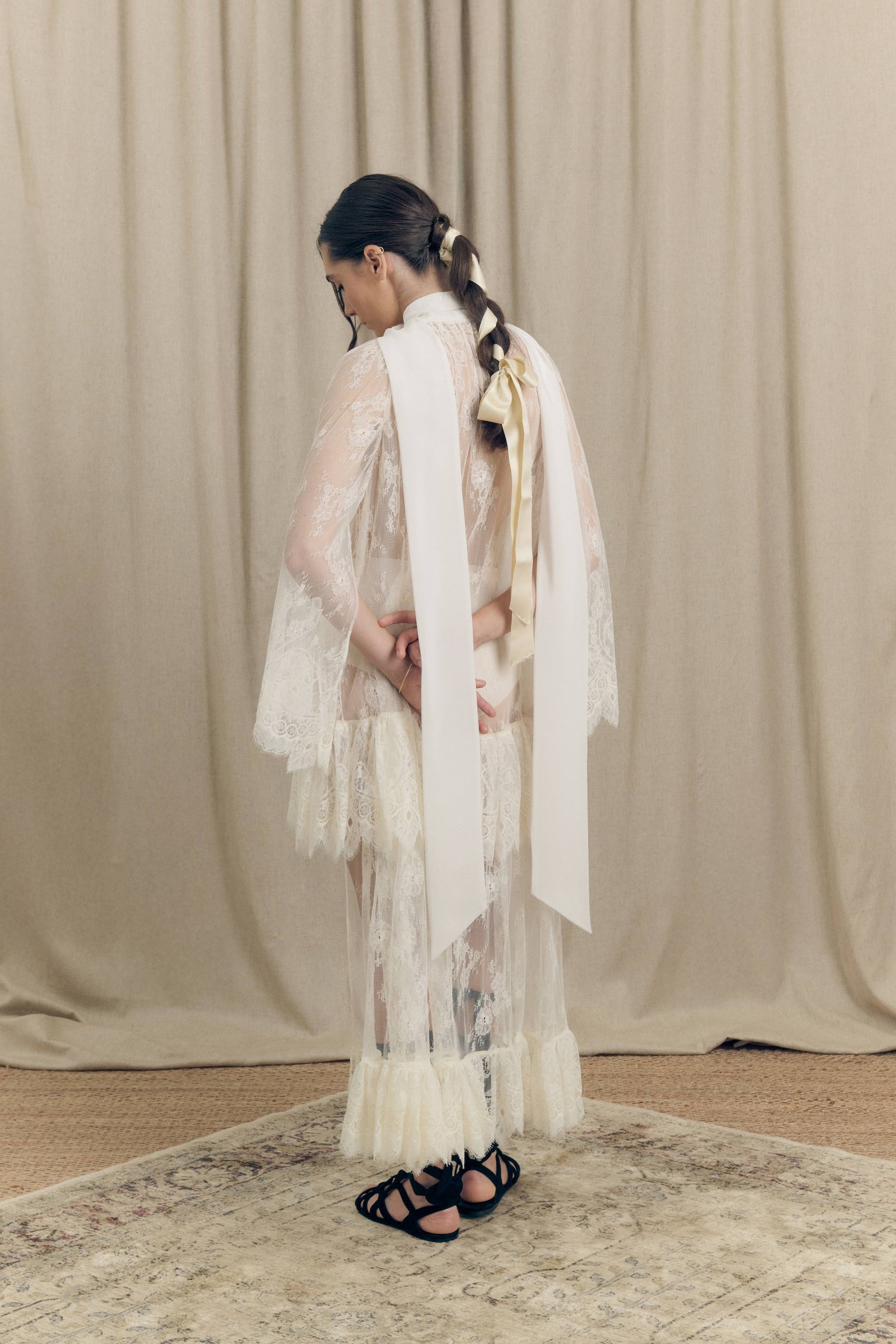Model wearing Botteghe Oscure asymmetrical French Chantilly lace dress with silk scarf – back view.