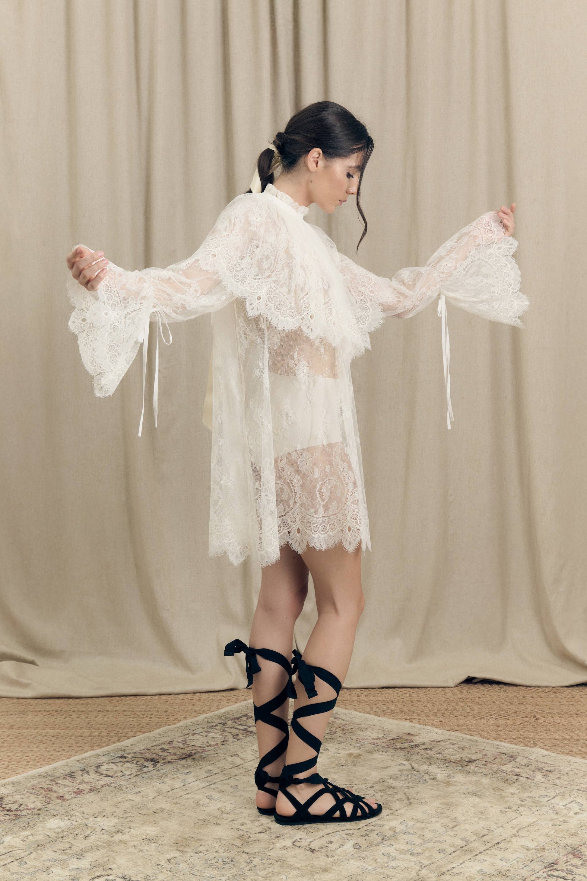 Model wearing Botteghe Oscure dress in French Chantilly lace with draped lace capelet and silk details – side view
