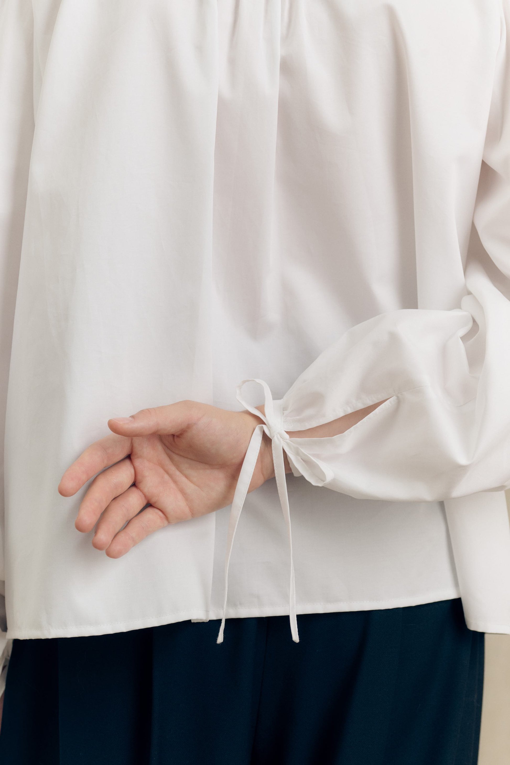 Model wearing a white cotton oversize shirt with ruffle collar and 1930s vintage buttons by Botteghe Oscure – detail cuff view