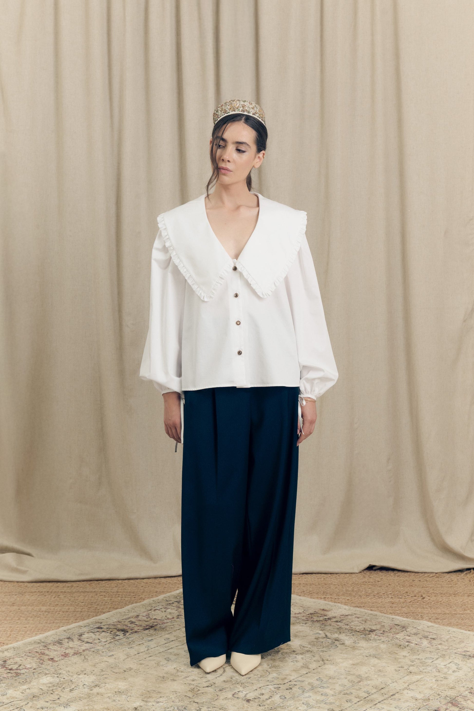 Model wearing a white cotton poplin oversize shirt with ruffle collar and 1930s vintage buttons and oversized black virgin wool tailored trousers by Botteghe Oscure – front view