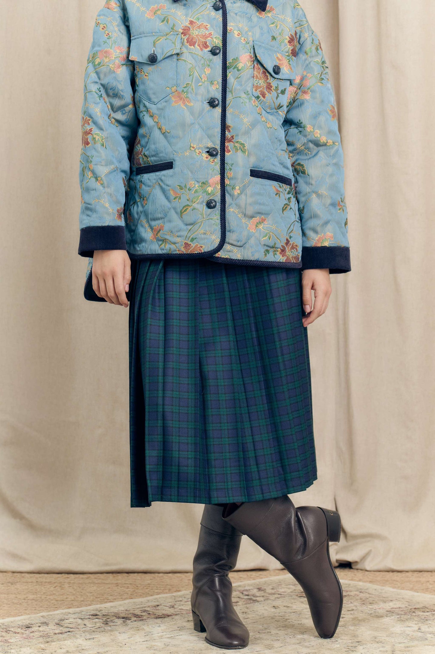 Model wearing the Botteghe Oscure Look 14 Academia skirt in Black Watch wool tartan with the floral quilted jacket