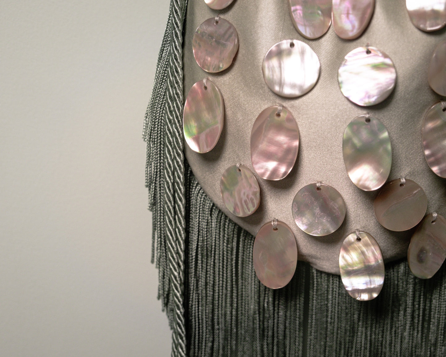 Detail of hand-applied natural mother-of-pearl discs on the sage green duchesse cotton reticule bag.