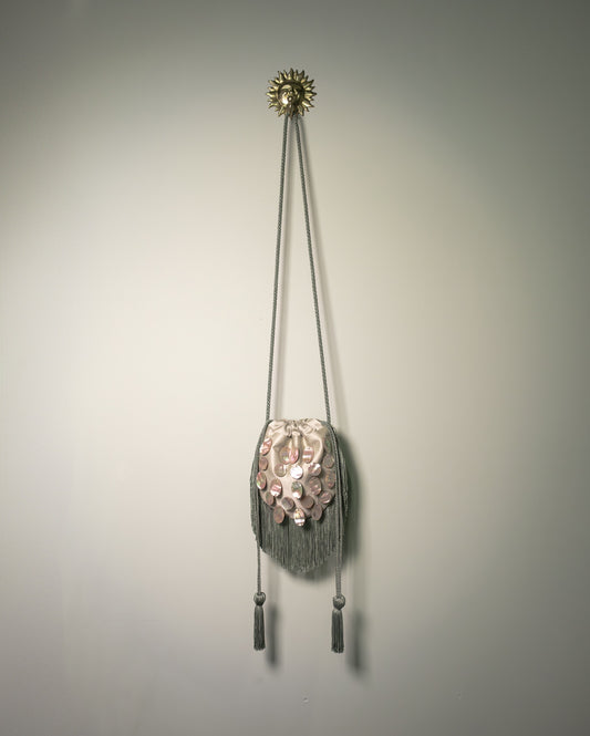 Sage green duchesse cotton reticule bag with hand-applied natural mother-of-pearl discs, decorative fringe and drawstring closure.