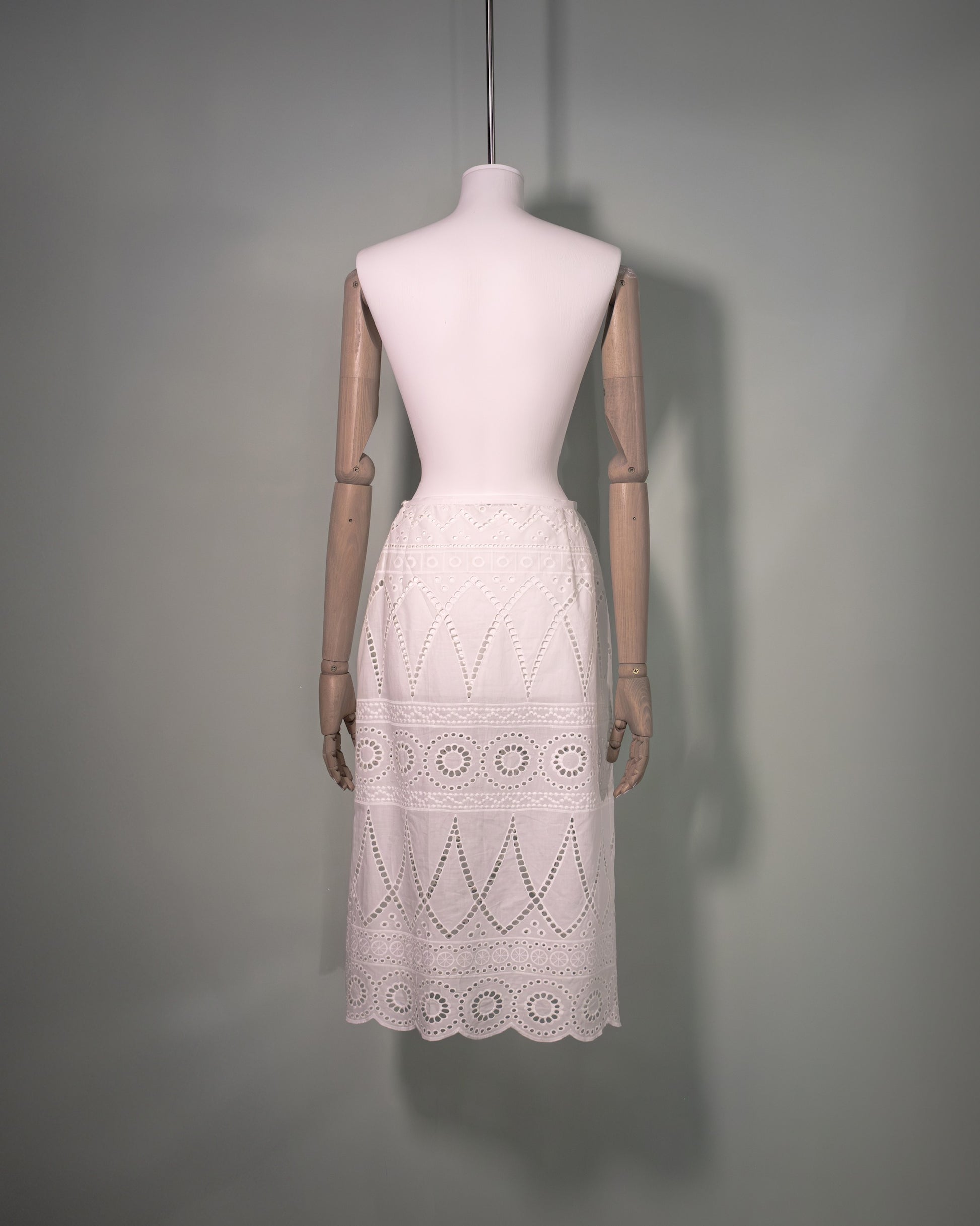 Back view of a white cotton batiste skirt featuring broderie anglaise embroidery and a scalloped hem.