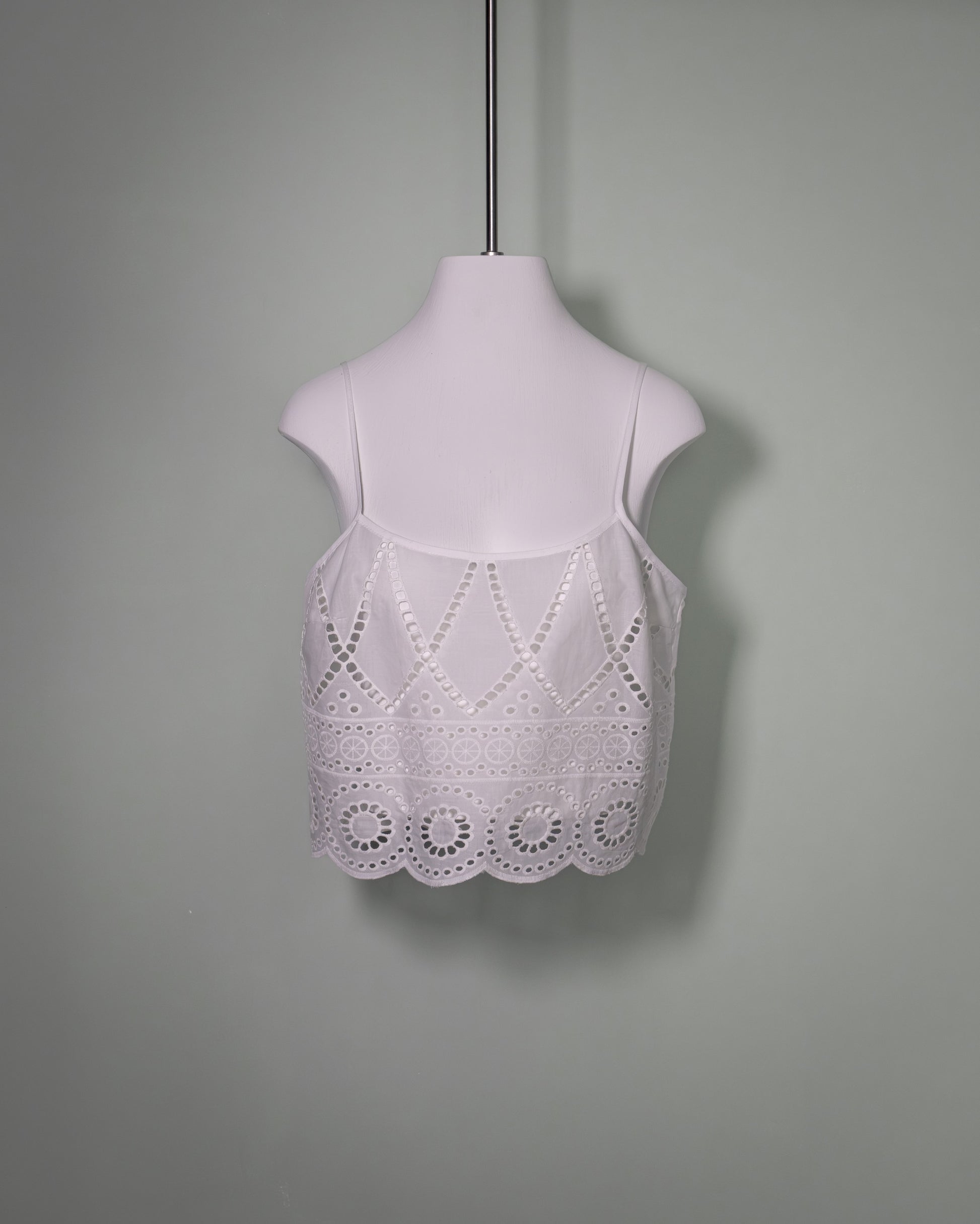 Front view of a white cotton batiste top featuring broderie anglaise embroidery and delicate spaghetti straps.
