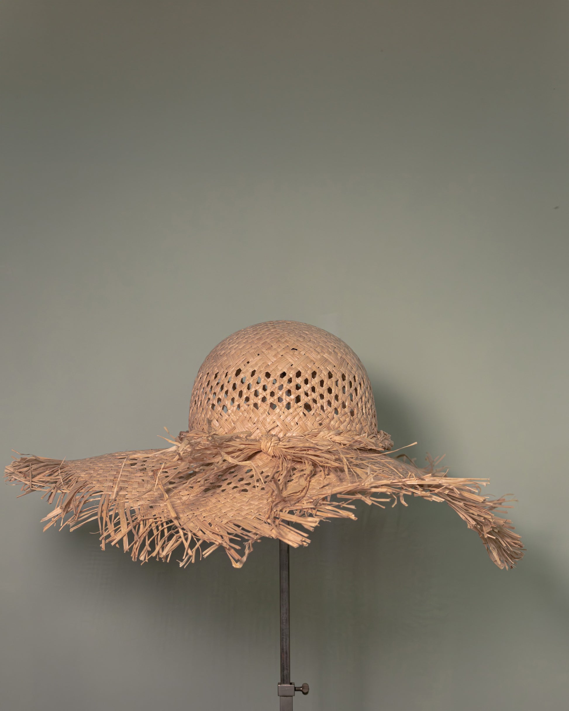 Side view of handmade Vienna straw hat with wide fringed brim and natural woven texture.