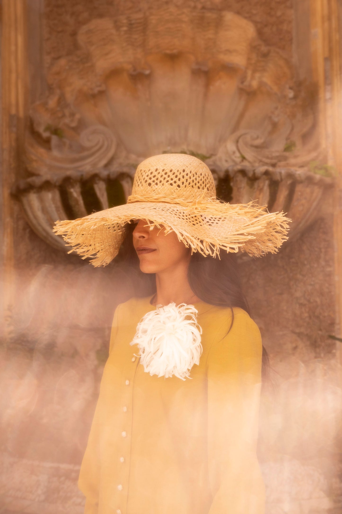 Model wearing a handmade Vienna straw hat with wide fringed brim, crafted in Tuscany.

