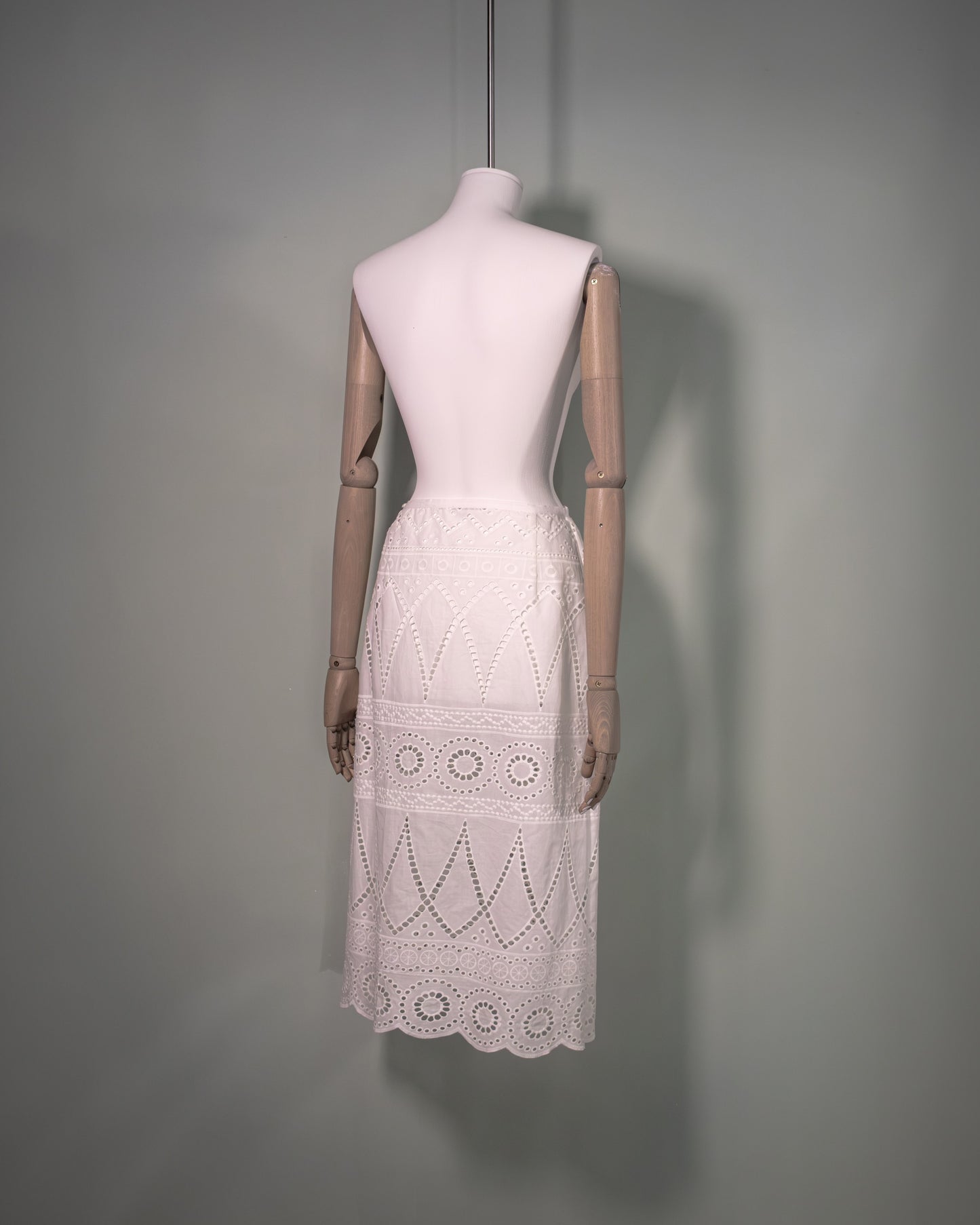 Side view of a white cotton batiste skirt featuring broderie anglaise embroidery and a scalloped hem.