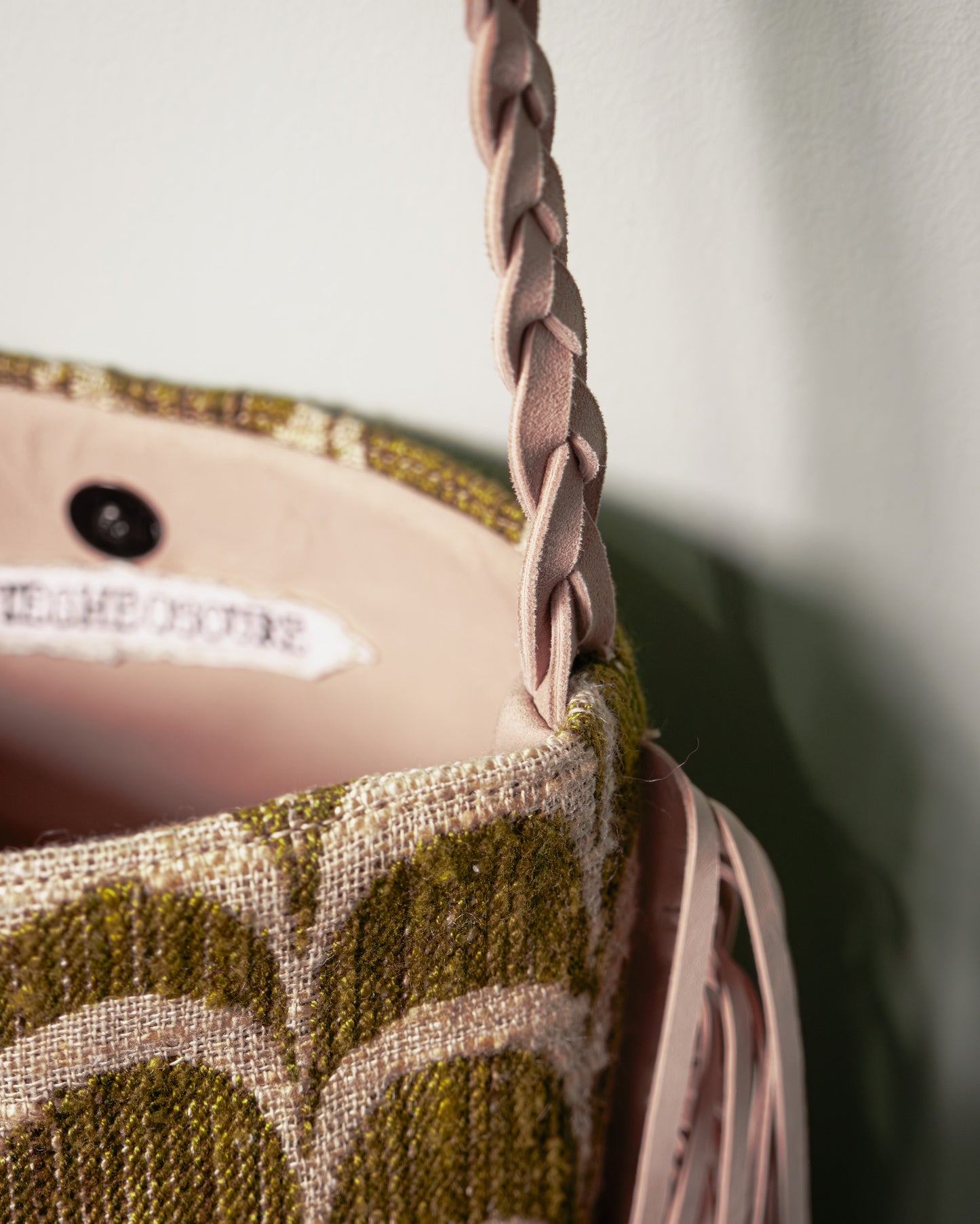 Close-up of the hand-braided nubuck leather shoulder strap on the Palmette Archive Bucket Bag.