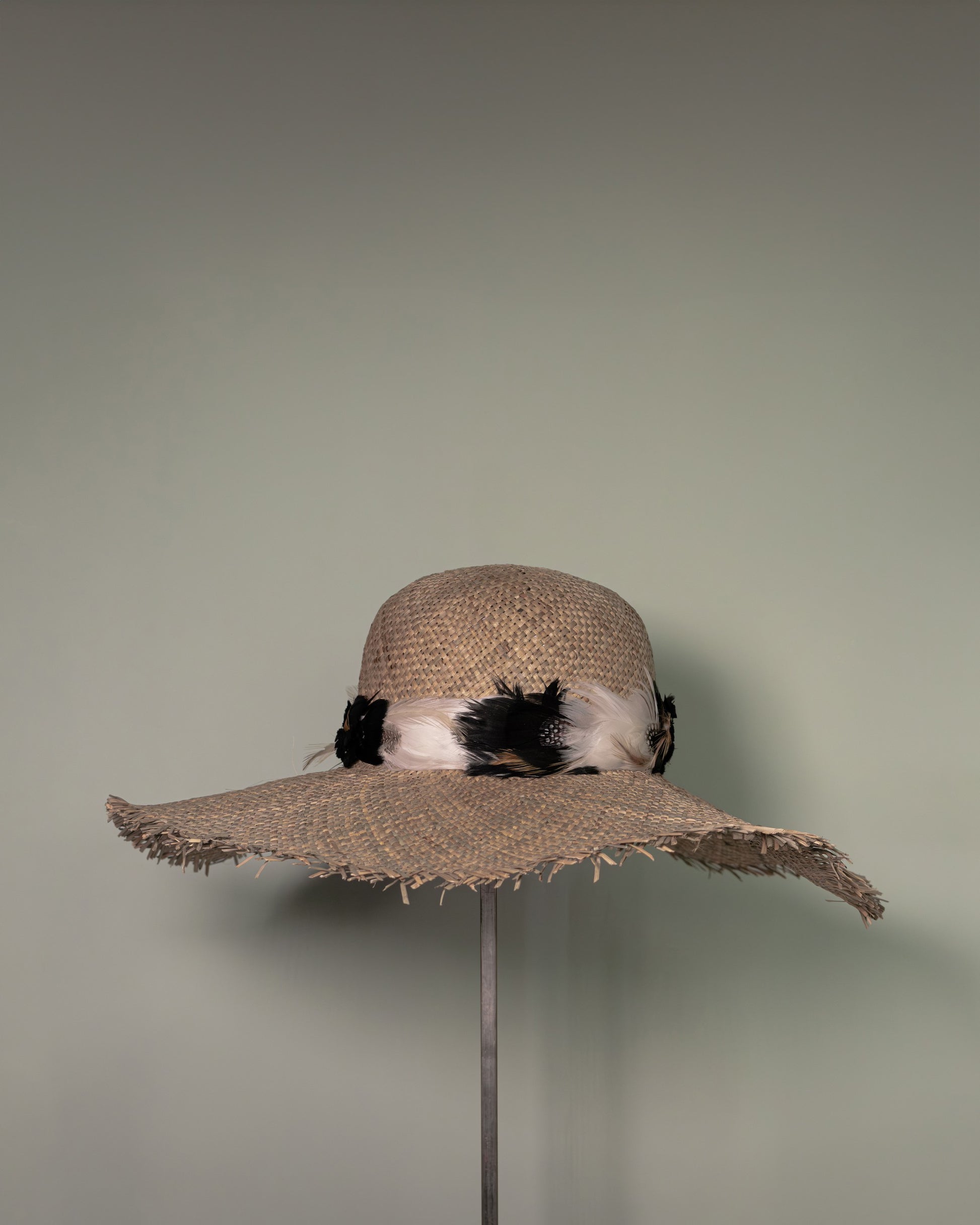 Rear view of handmade straw hat with feather decoration by Botteghe Oscure.