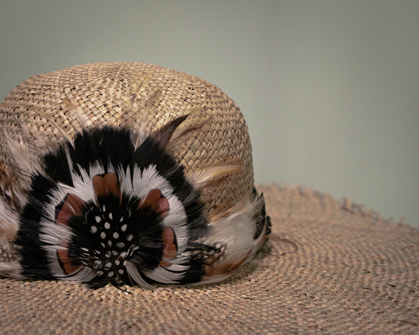 Close-up of handwoven straw hat with handcrafted feather embellishment.