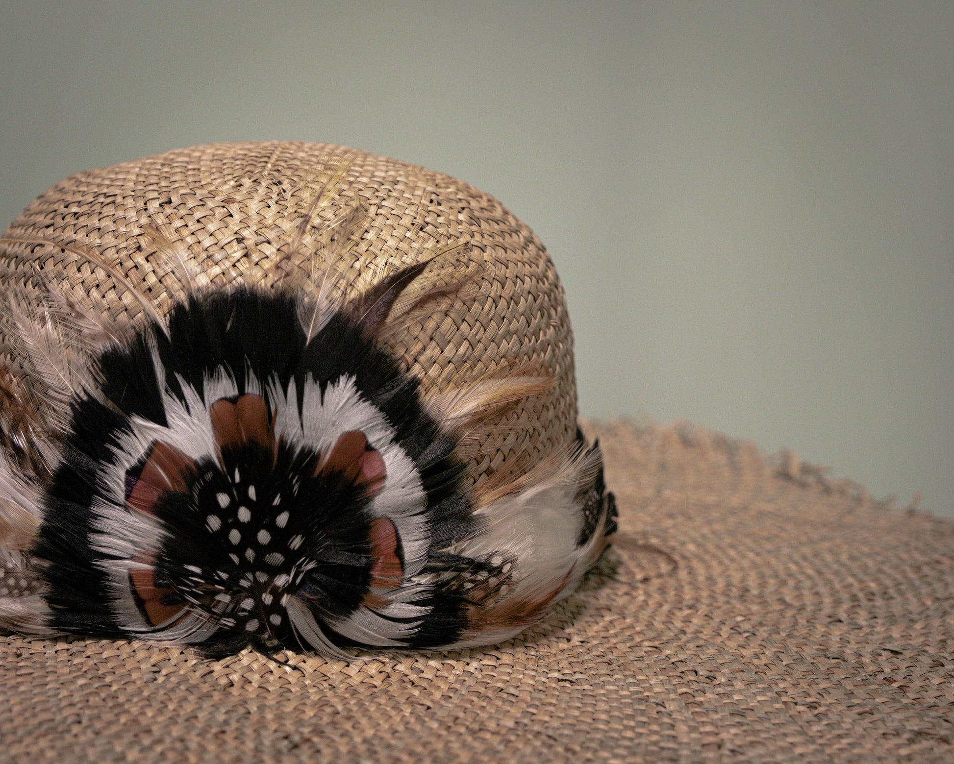 Close-up of handwoven straw hat with handcrafted feather embellishment.