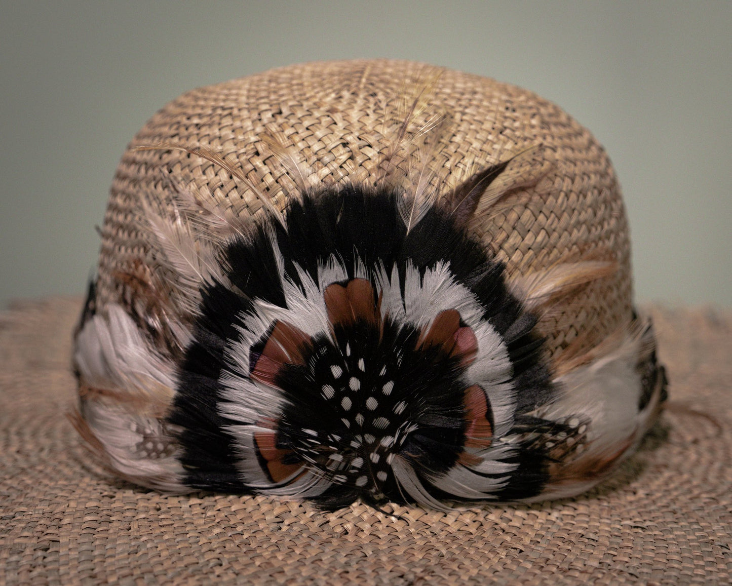 Detailed view of handcrafted feather decoration on handmade straw hat by Botteghe Oscure.