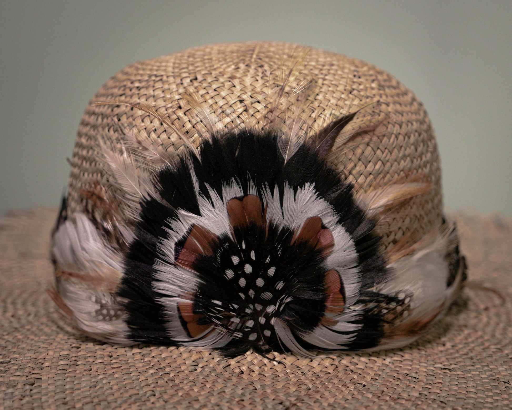 Detailed view of handcrafted feather decoration on handmade straw hat by Botteghe Oscure.