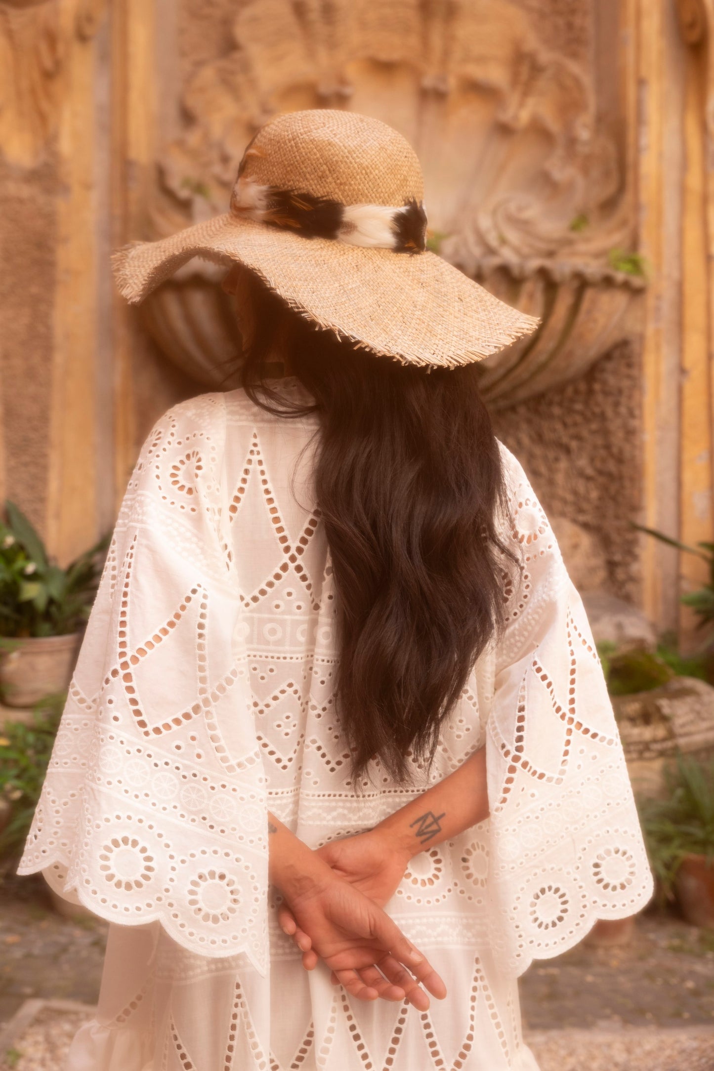 Handmade feather straw hat worn with embroidered garment by Botteghe Oscure.