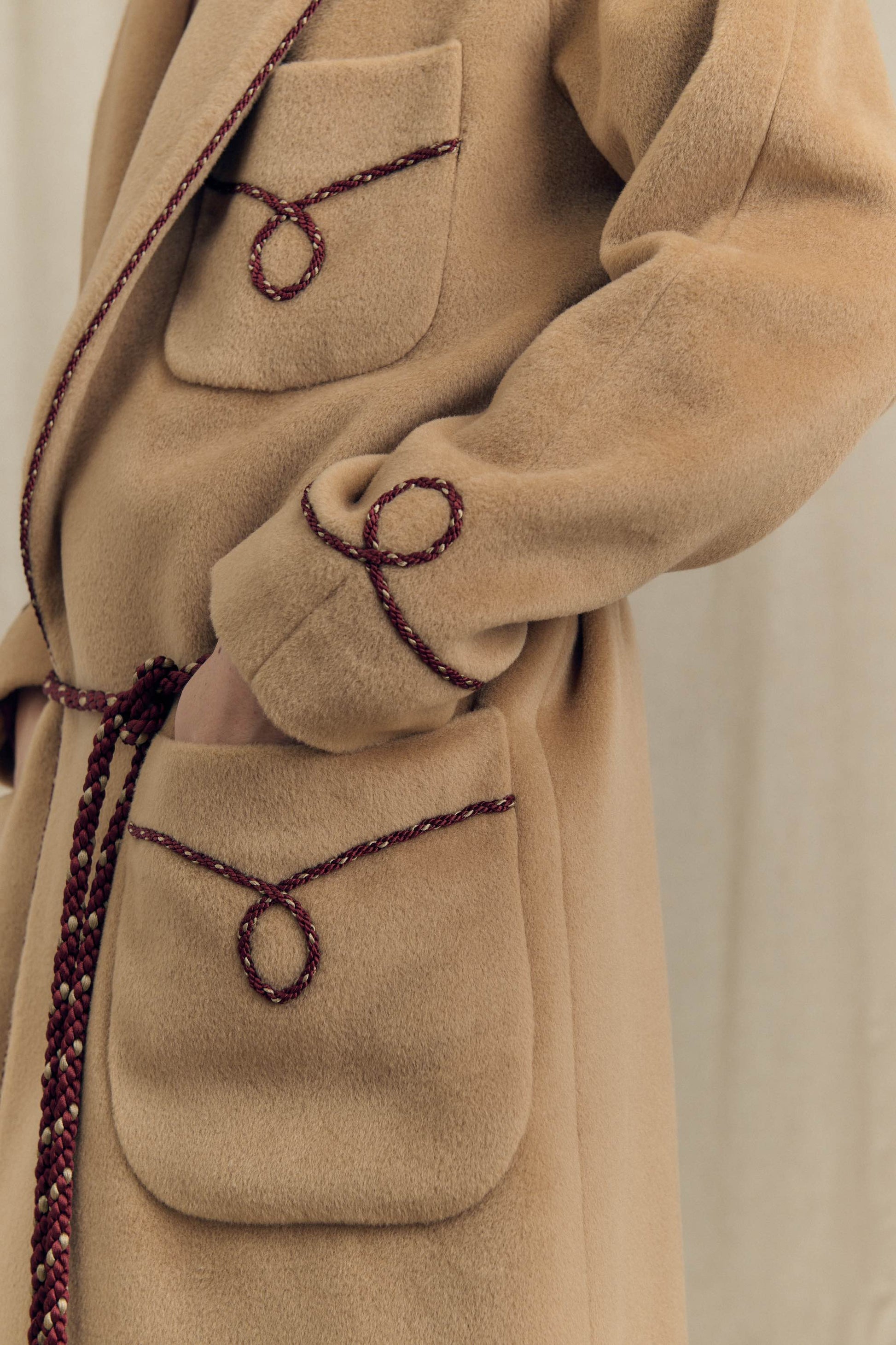 Close-up of perlé cord belt with tasselled ends on camel combed wool wrap coat, Botteghe Oscure lookbook.