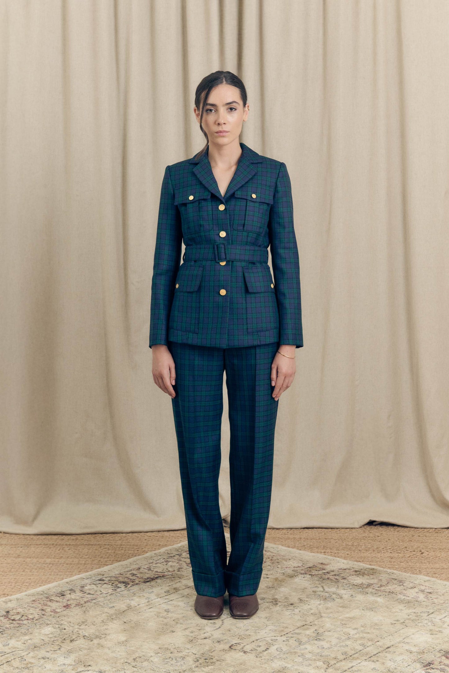 Model wearing belted military blazer by Botteghe Oscure and matching Black Watch tartan trousers, full front view.