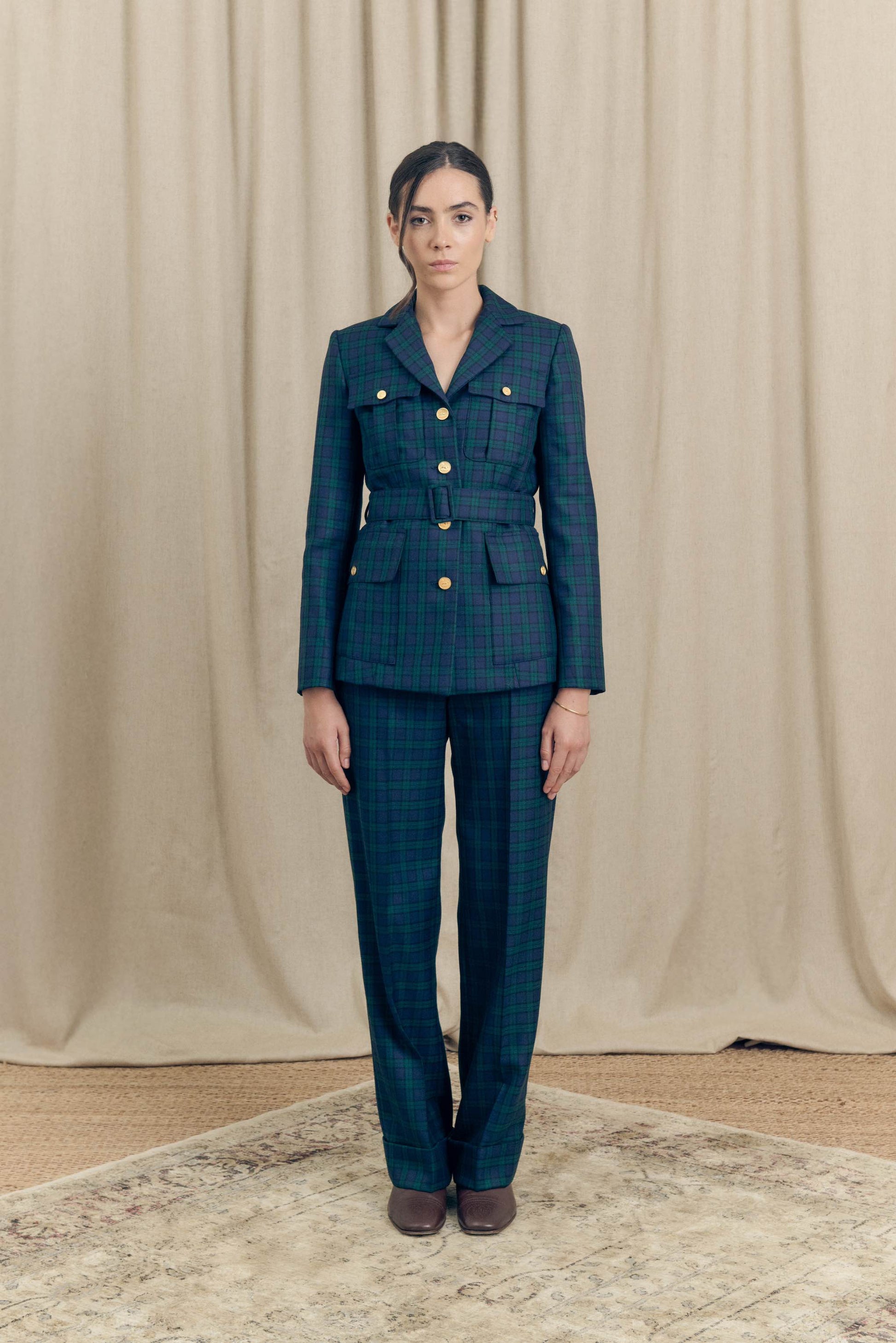 Model wearing belted military blazer by Botteghe Oscure and matching Black Watch tartan trousers, full front view.