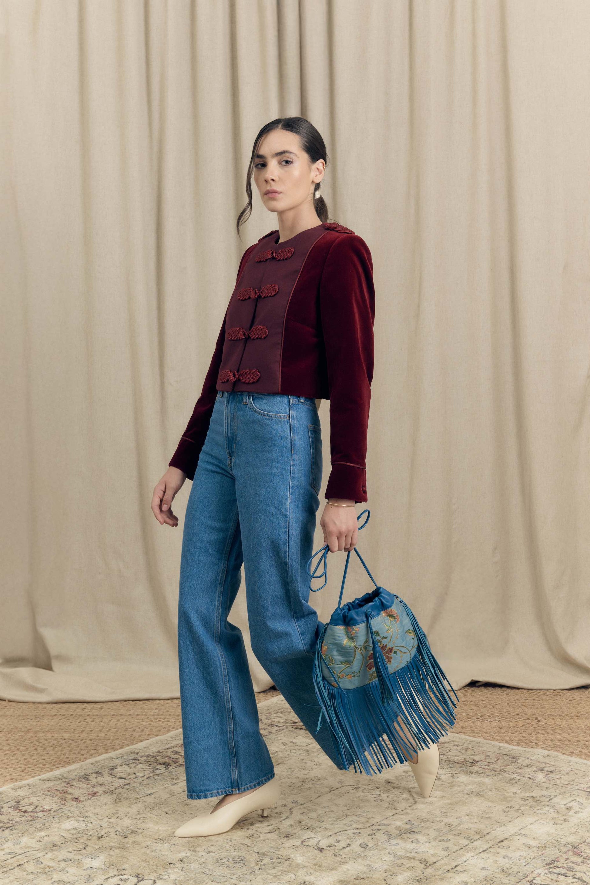 Model wearing Botteghe Oscure Brandebourg bordeaux velvet jacket styled with denim, contemporary lookbook styling.