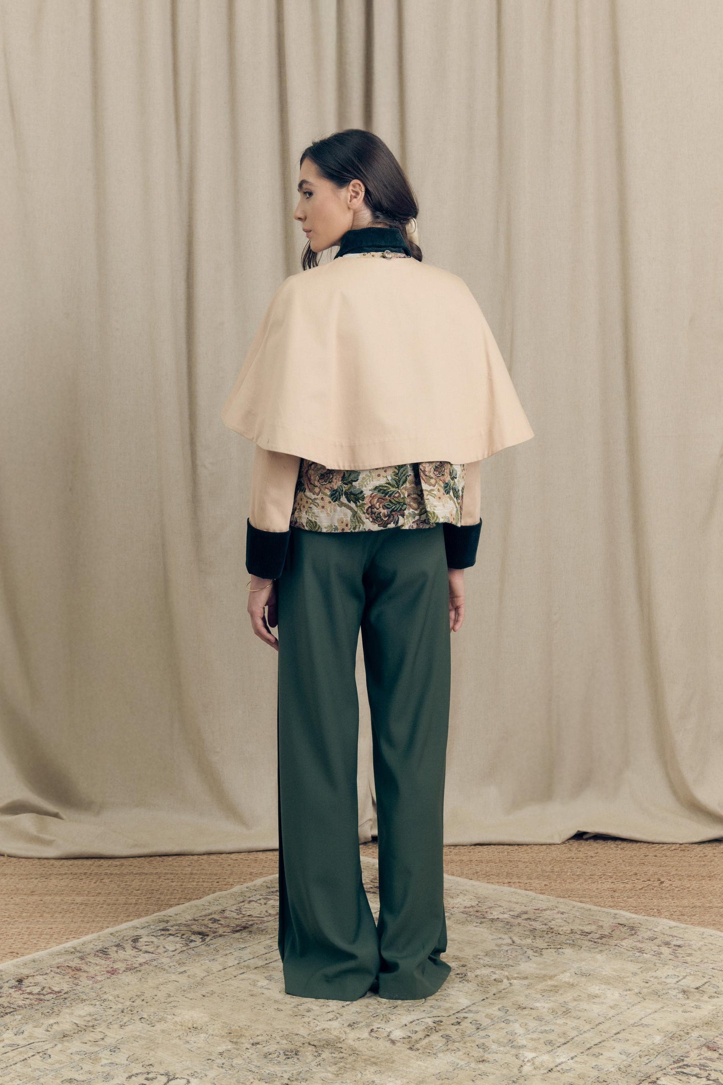 Back view of the Heatherfield Jacket by Botteghe Oscure, featuring a removable cotton twill capelet, deep back pleat, and floral jacquard panel with dark green velvet collar and cuffs.