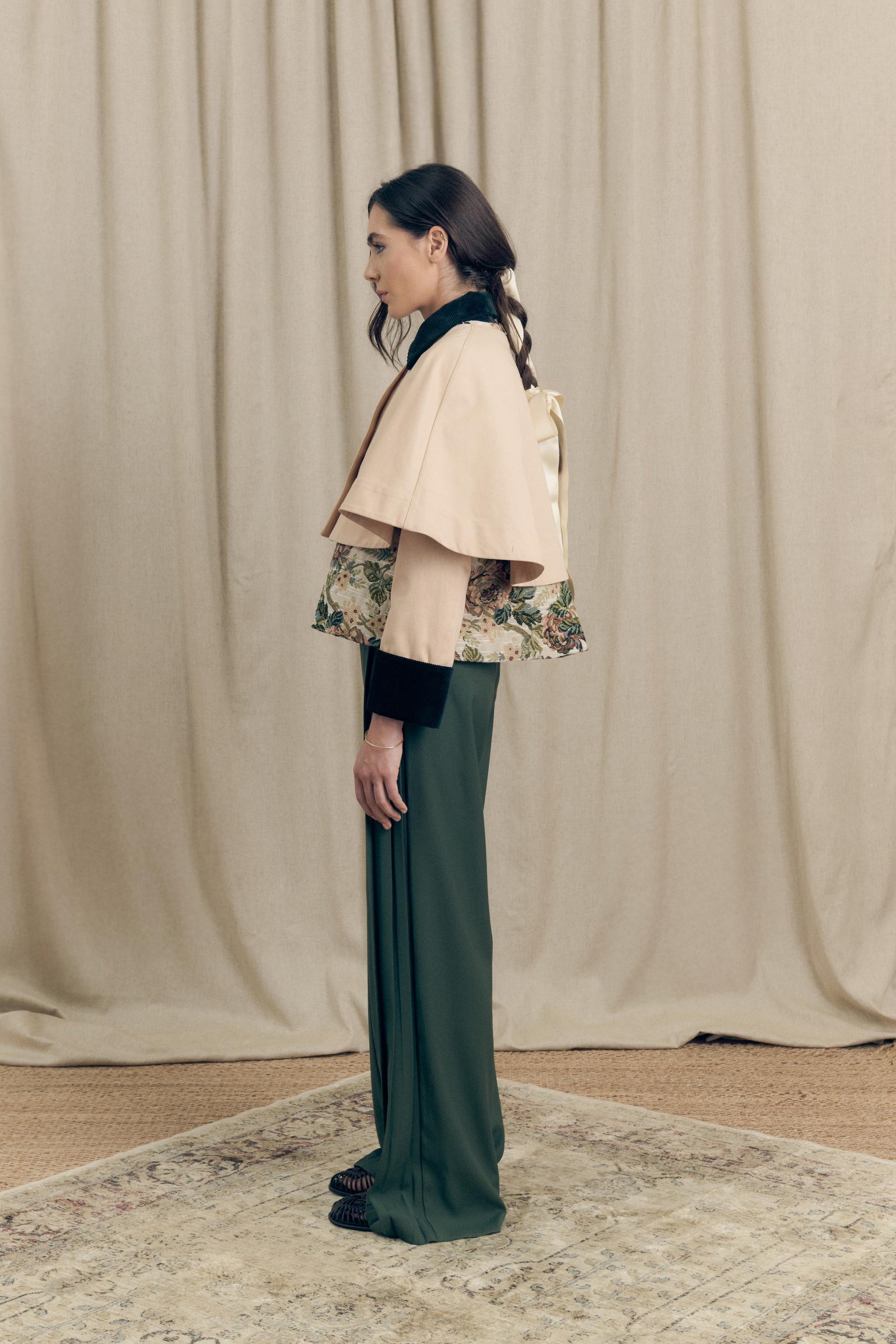 Side view of the Heatherfield Jacket by Botteghe Oscure, highlighting the slightly flared silhouette, removable capelet, and refined mix of floral jacquard and dark green velvet detailing.