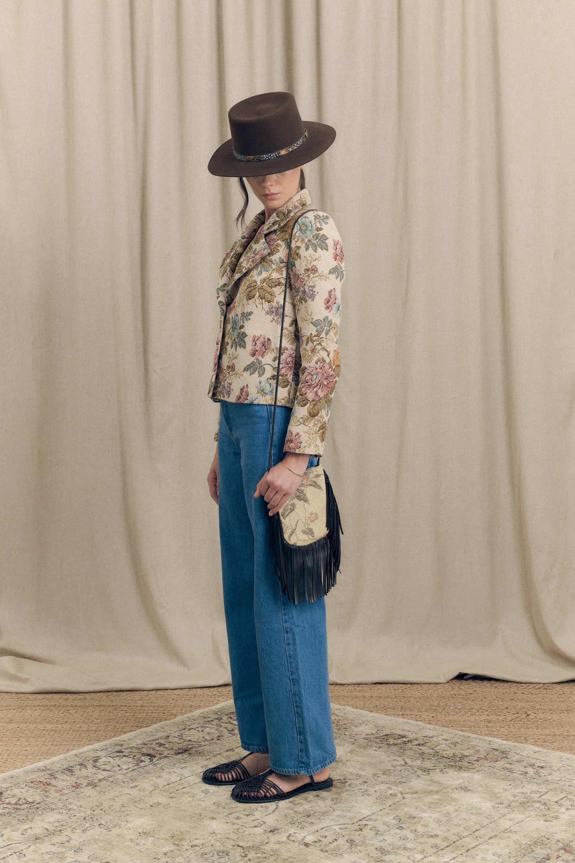 Side view of floral jacquard blazer by Botteghe Oscure with structured shoulders, vintage tapestry pattern and crossbody mini bag with leather fringes.