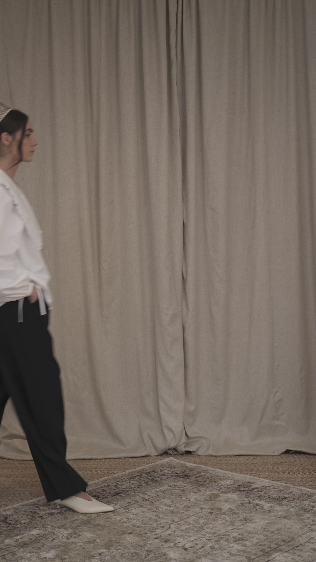 Model wearing white cotton oversize shirt with ruffle collar and vintage mother-of-pearl buttons, oversized black taolired trousers in virgin wool by Botteghe Oscure